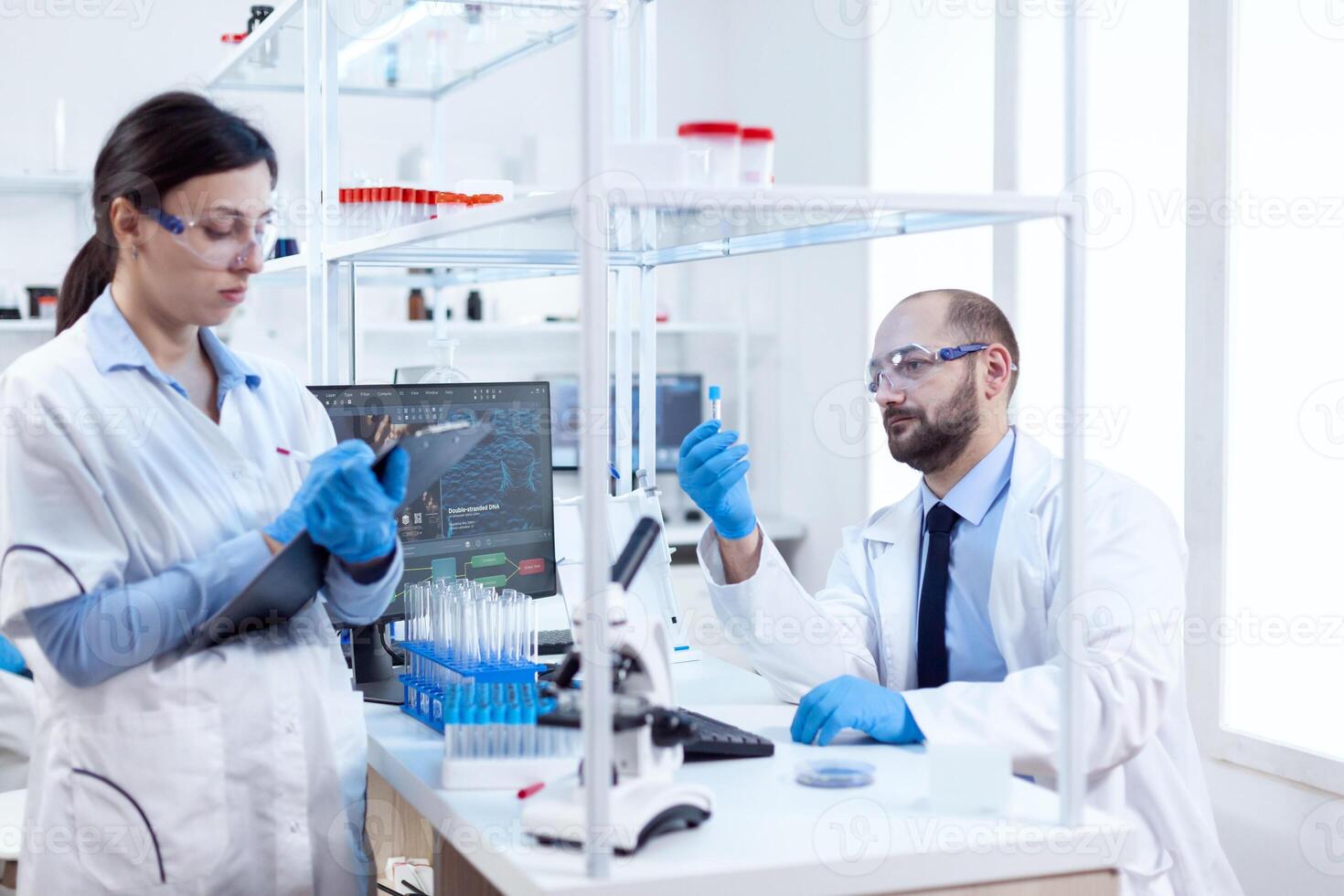 jong wetenschapper analyseren en aan het doen experimenten chemie laboratorium. team van chemisch chemici werken samen in steriel microbiologie laboratorium aan het doen Onderzoek. foto