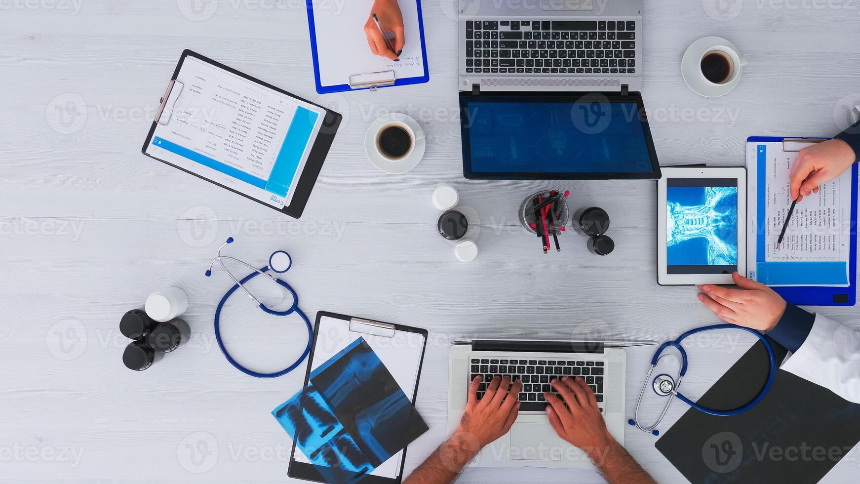 top visie van specialist dokter analyseren menselijk hersenen gebruik makend van tablet Aan flatlay zittend Aan bureau in kliniek met medisch apparatuur. assistenten nemen aantekeningen Aan laptop en klembord, onderzoeken Aan kopiëren ruimte foto