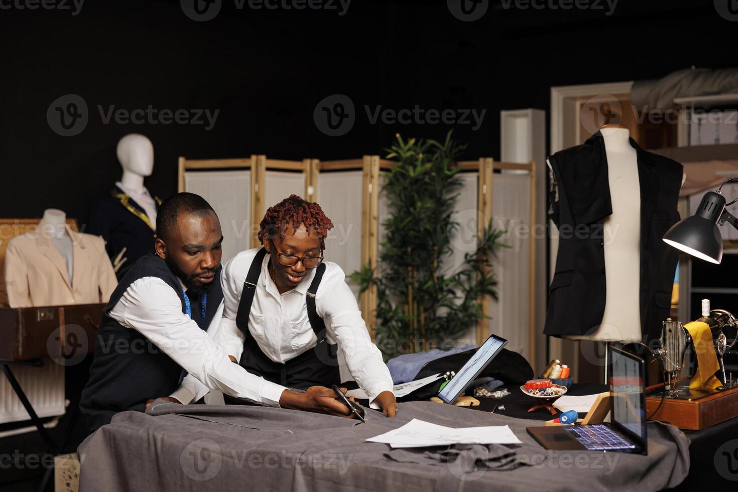 hoog einde fabricage pakmakers snijdend textiel materiaal met schaar in maatwerk studio, ontwerpen kleermakers- mode kleren. naaisters werken Aan op maat gemaakt cliënt commissie foto