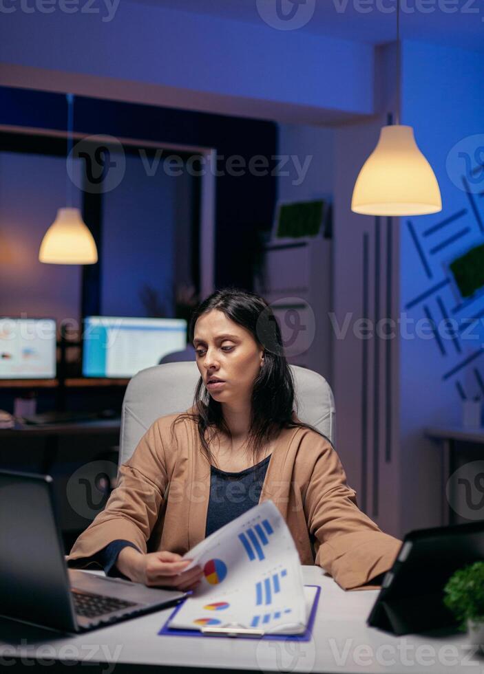 ondernemer zoeken door documenten naar af hebben een deadline in de avond. bedrijf vrouw werken na een tijdje Bij de kantoor naar af hebben een zakelijke baan gebruik makend van tablet pc. foto