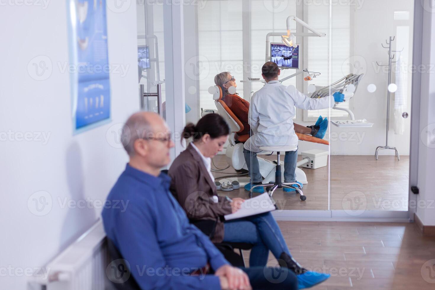 tandarts met senior geduldig analyseren tanden radiografie röntgenstraal in overleg kantoor zittend Aan stoel. stomatologie gang met mensen vulling behandeling afspraak het formulier. foto