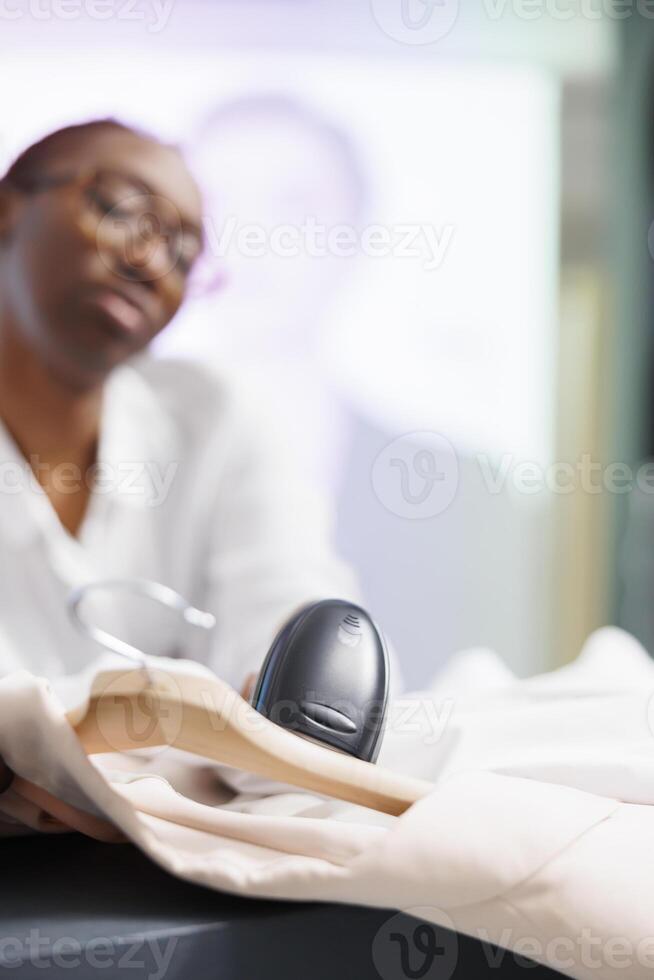 kleding op te slaan Kassa scannen items Bij uitchecken teller naar helpen klant maken aankoop. boodschappen doen centrum winkel Afrikaanse Amerikaans vrouw werknemer gebruik makend van streepjescode scanner Bij contant geld registreren foto