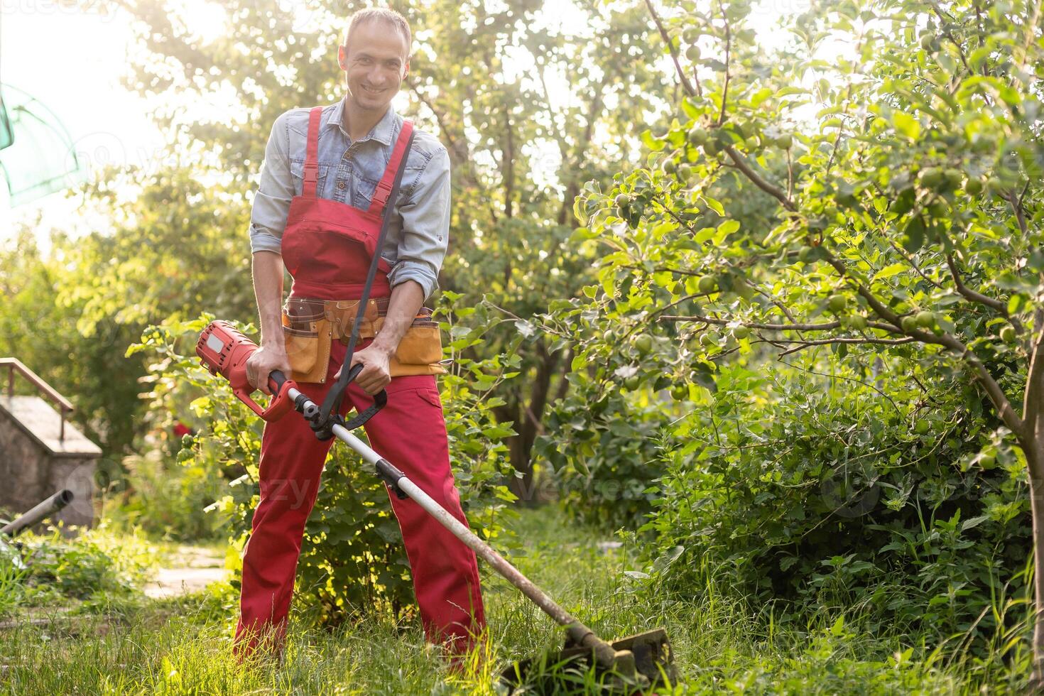 gras maaien gras met elektrisch gazon maaier. tuin werk concept. Mens maait de gras met hand- maaier in de tuin foto