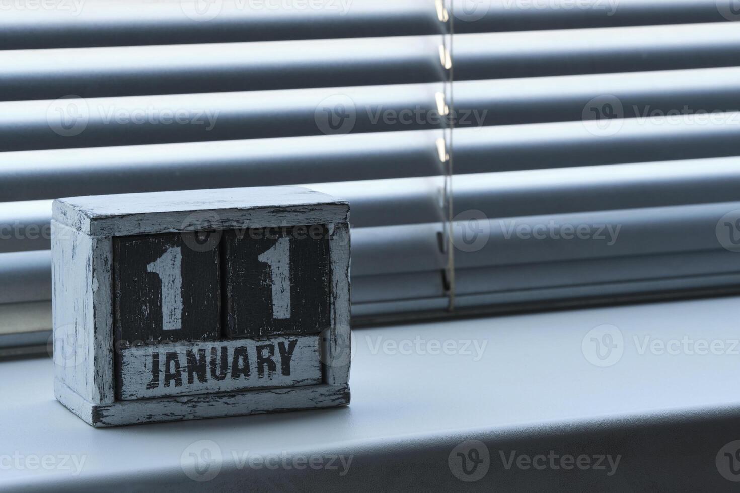 ochtend- januari 11 Aan houten kalender staand Aan venster met jaloezieën. foto