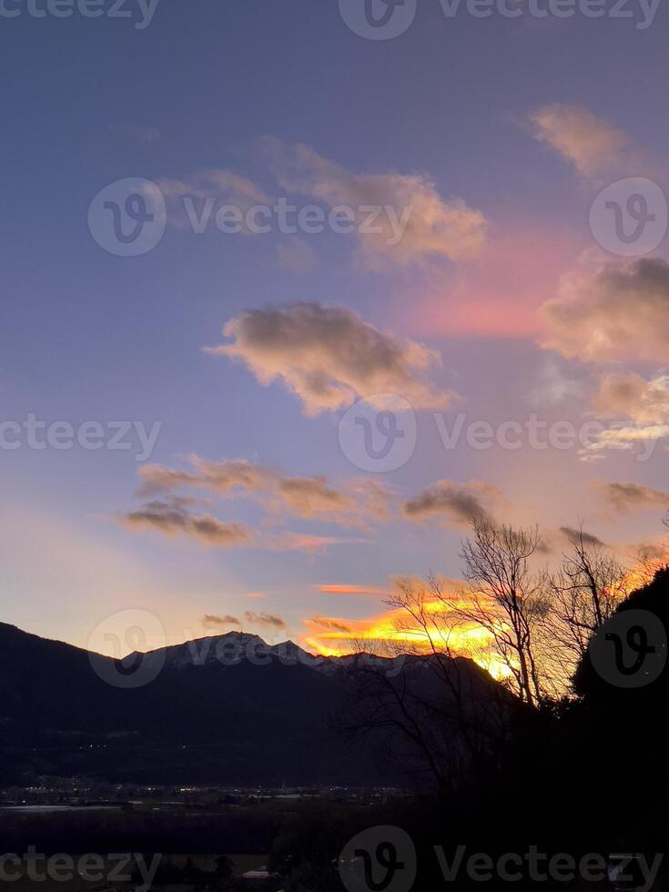 een zonsondergang over- een berg reeks met wolken foto