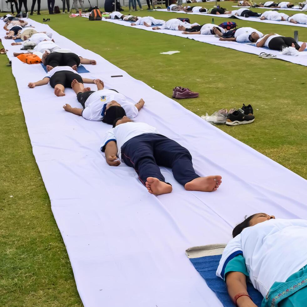 nieuw Delhi, Indië, juni 21, 2023 - groep yoga oefening sessie voor mensen Bij Yamuna sport- complex in Delhi Aan Internationale yoga dag, groot groep van volwassenen Bijwonen yoga klasse in krekel stadion foto