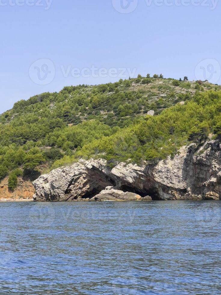 een rotsachtig eiland met een grot in de midden- van de water foto