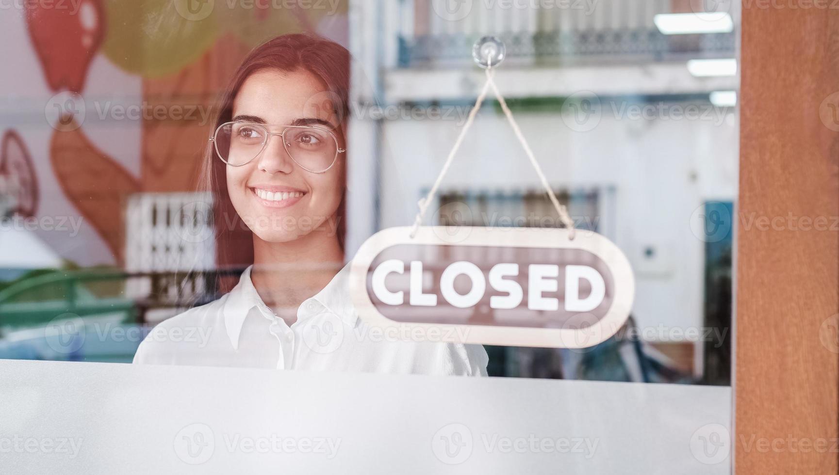 gelukkig klein zakelijk meisje verandert gesloten om teken op raam te openen glimlachend naar buiten kijkend foto