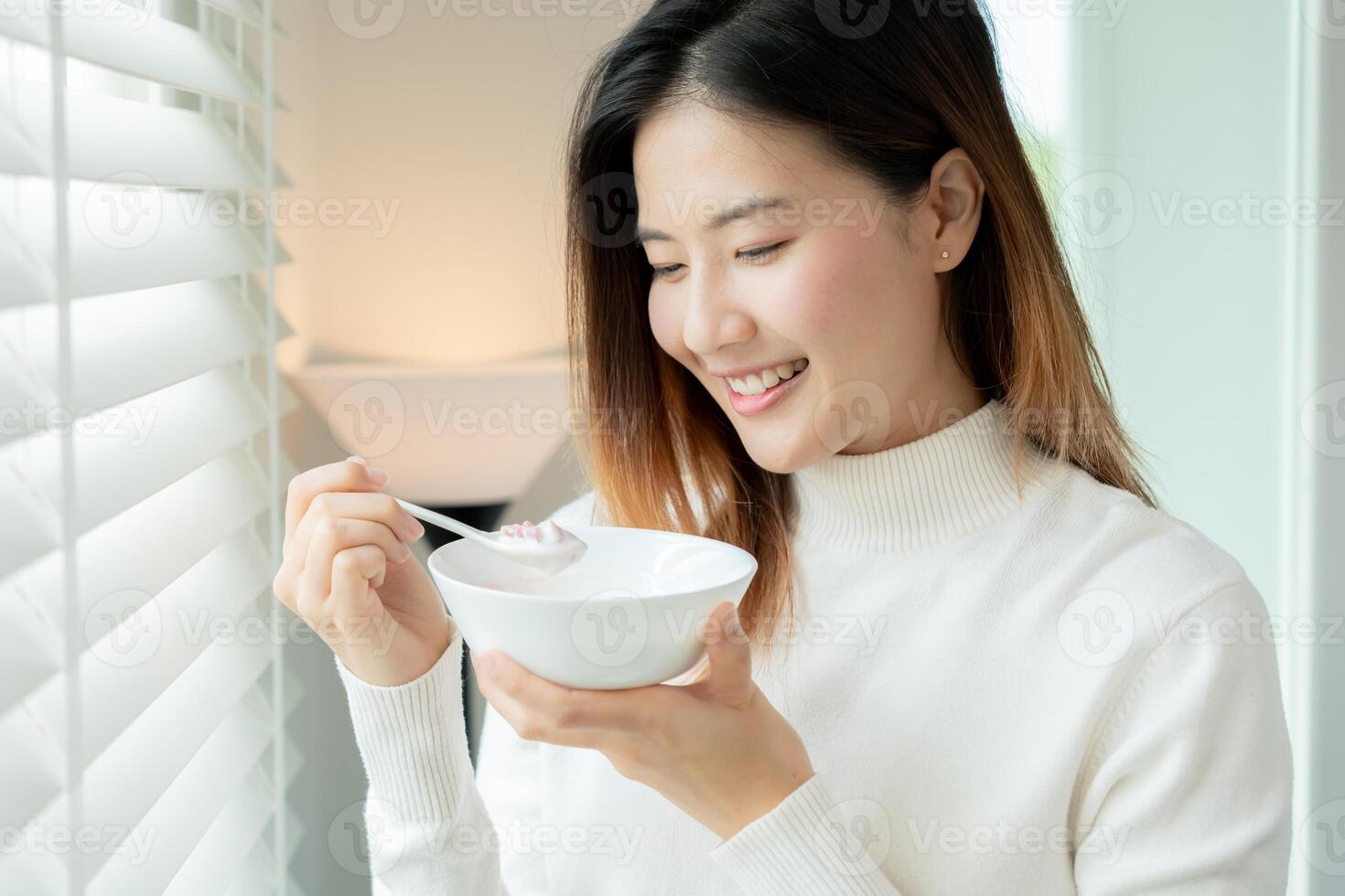 gezond voedsel. mooi vrouw meisje genieten eten yoghurt, muesli, vers fruit Aan ontbijt Gezondheid in huis. gelukkig jong vrouw glimlach Aan ochtend- mooi zo emotie. diëten, ontgiften, eetpatroon, schoon eten, vegetarisch foto