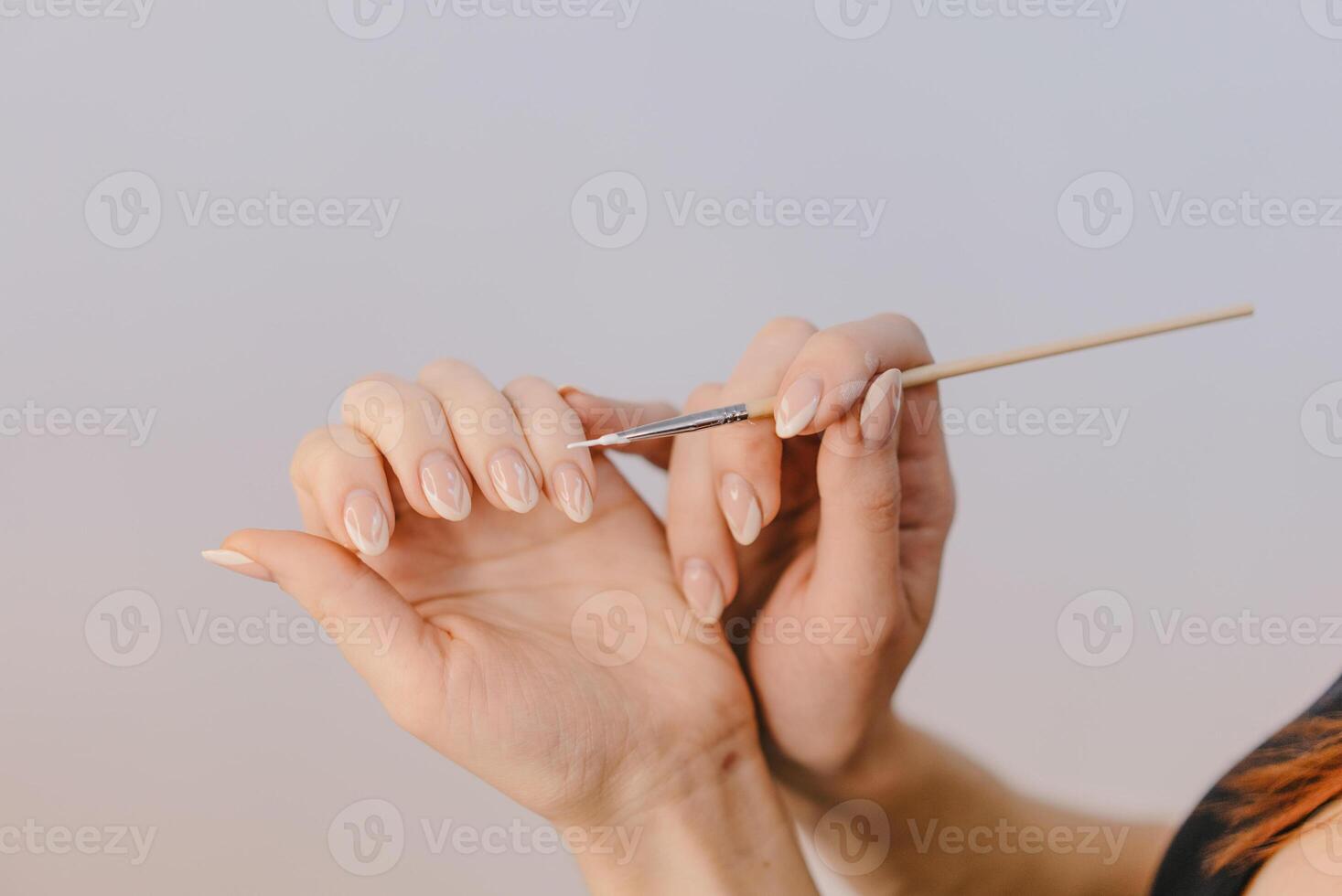 vrouw met goed verzorgd handen covers haar nagels door gel-vernis gebruik makend van een dun borstel Aan een wit achtergrond. detailopname foto