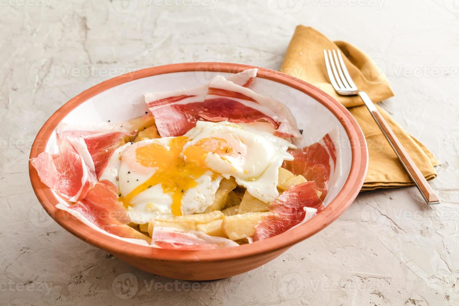 gebroken gebakken eieren met aardappelen en Iberische gerookte ham in Spaans restaurant foto