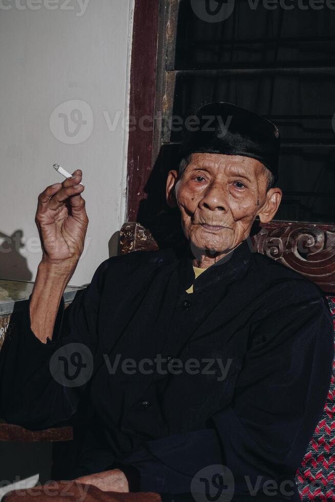 portret van een ouderen Aziatisch Mens roken een sigaret. foto