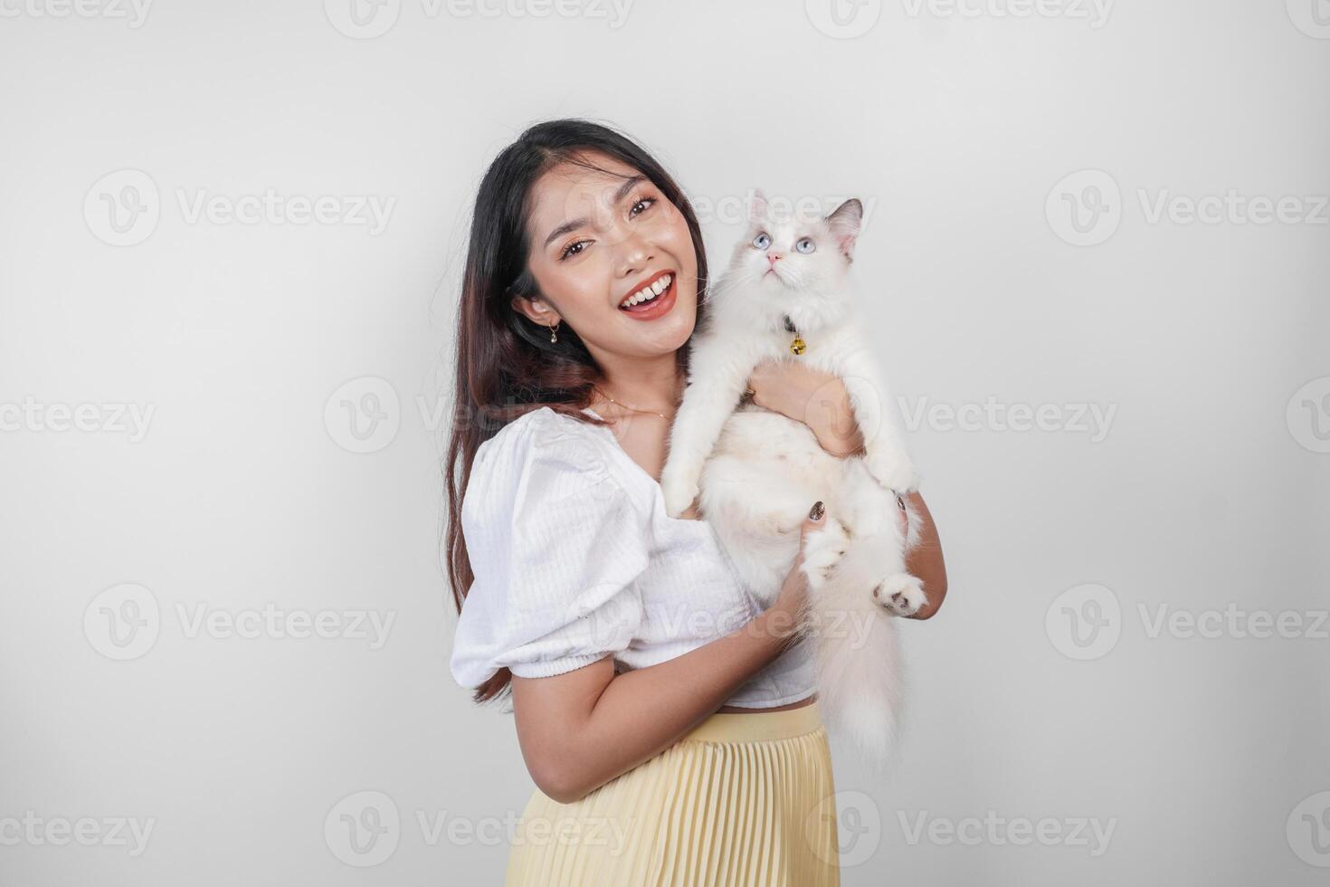 portret van jong Aziatisch vrouw Holding schattig lappenpop kat met blauw ogen. vrouw knuffelen haar schattig lang haar- pot geïsoleerd door wit achtergrond. aanbiddelijk huiselijk huisdier concept. foto