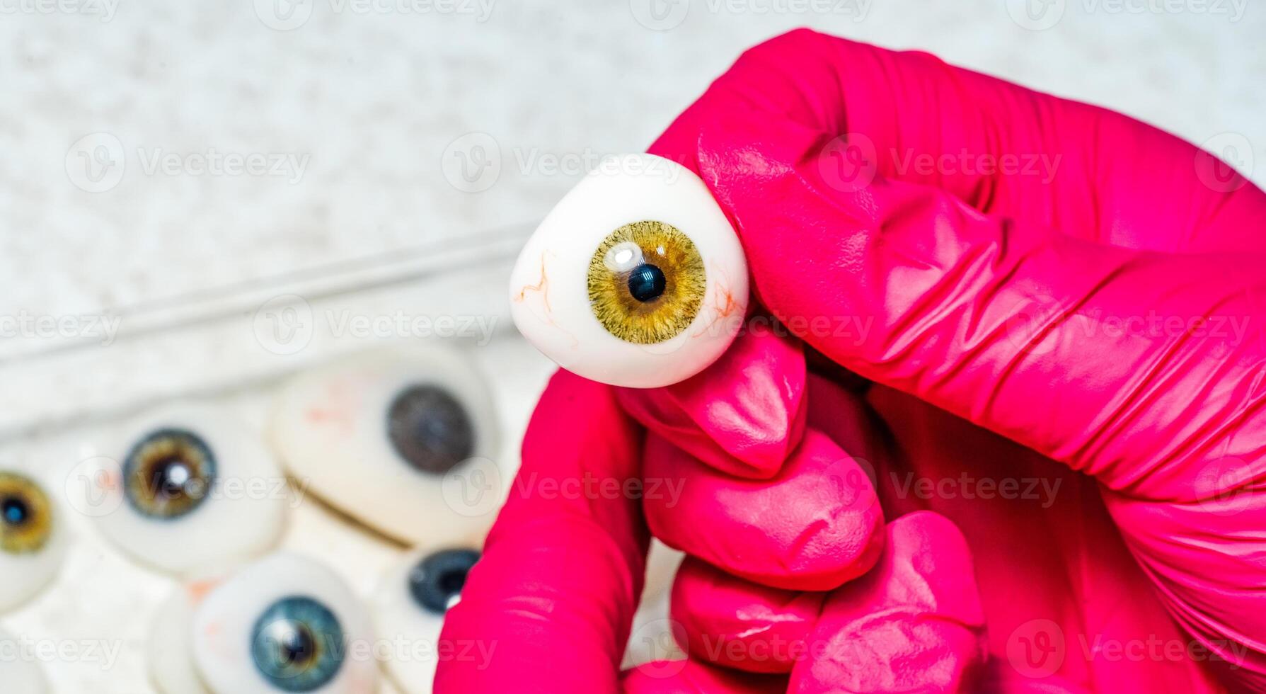 oogarts of chirurg houdt een oog, oogbol prothese in handen . concept foto voor oculair prothese, diagnose behandeling van oogheelkundig ziekten, chirurgisch operaties Aan ogen. detailopname.