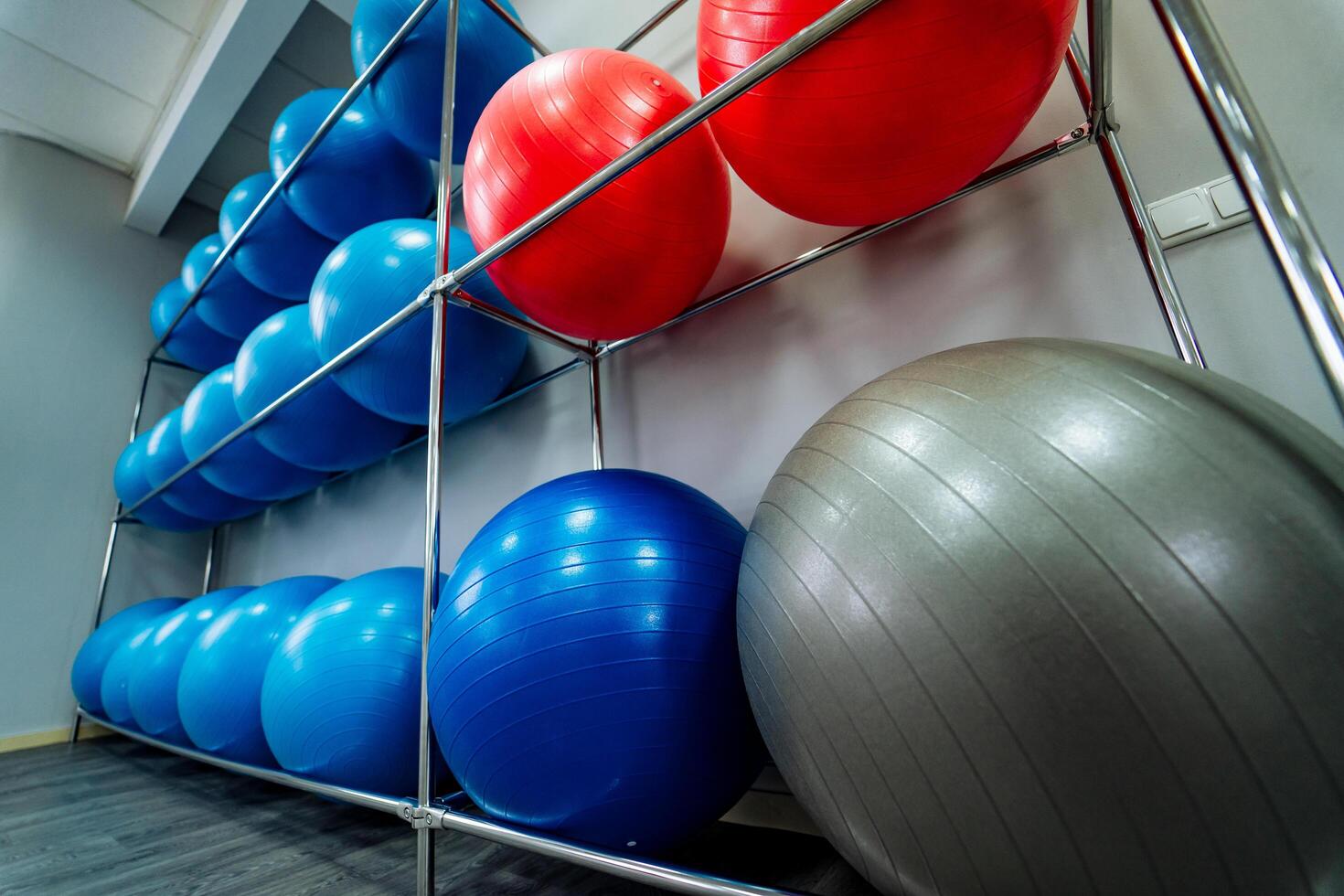 groot blauw, rood en grijs geschiktheid ballen in drie rijen in een staan in de buurt de grijs muur in Sportschool. geschiktheid yoga en pilates hal met sport apparatuur. detailopname foto