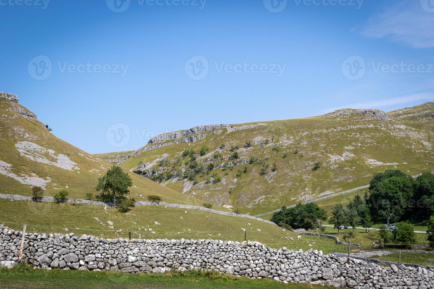 idyllisch landelijk landschap met steen muren en rollend heuvels onder een Doorzichtig blauw lucht. foto