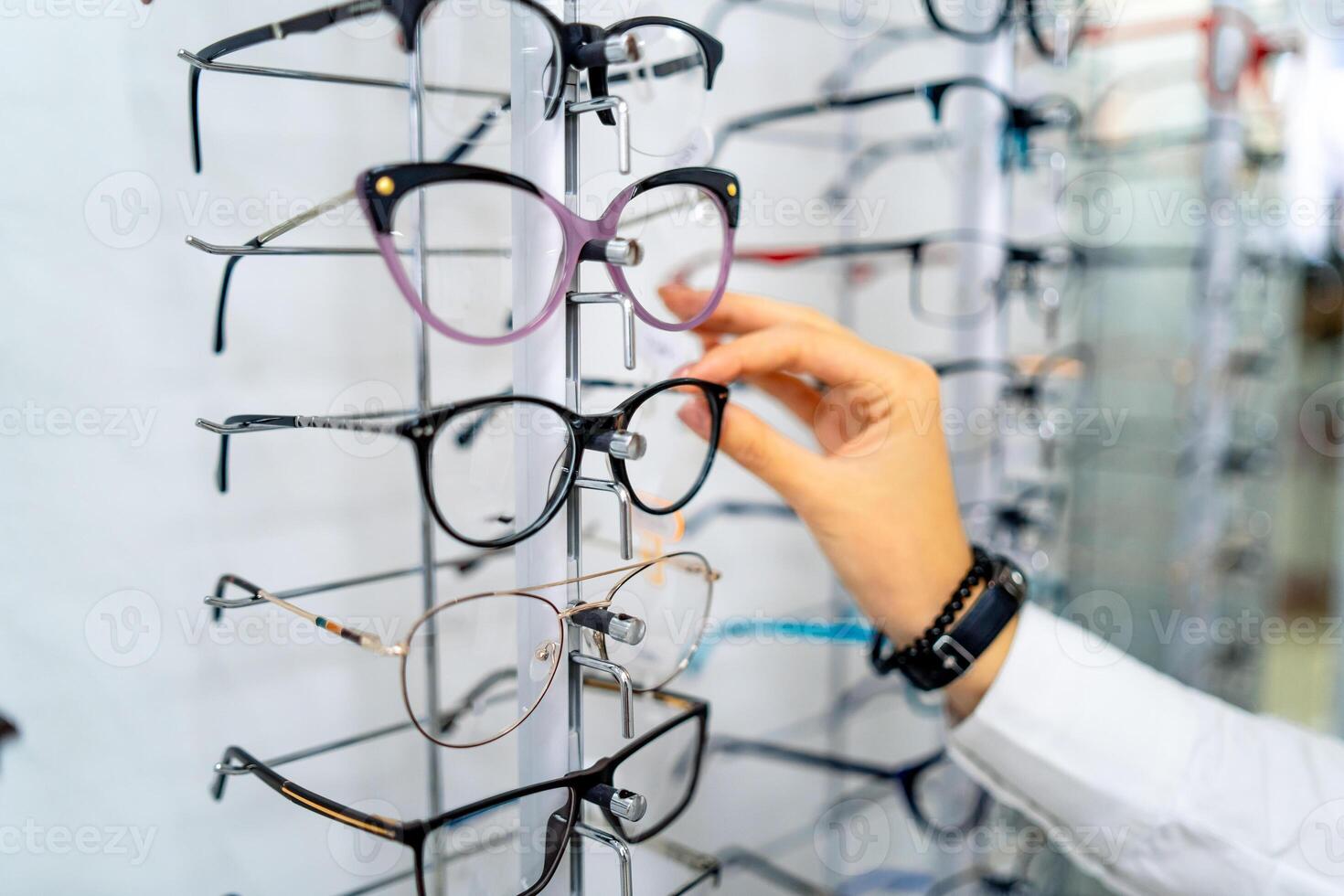 rij van bril Bij een opticiens. bril winkel. staan met bril in de op te slaan van optiek. vrouw hand- kiezen bril. presenteren bril. foto