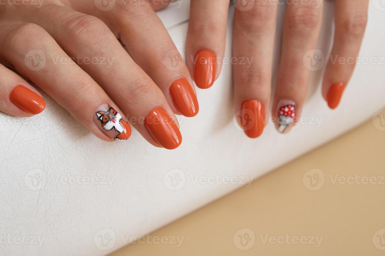 vrouwelijke handen met oranje manicure met een patroon onder een glanzende top foto