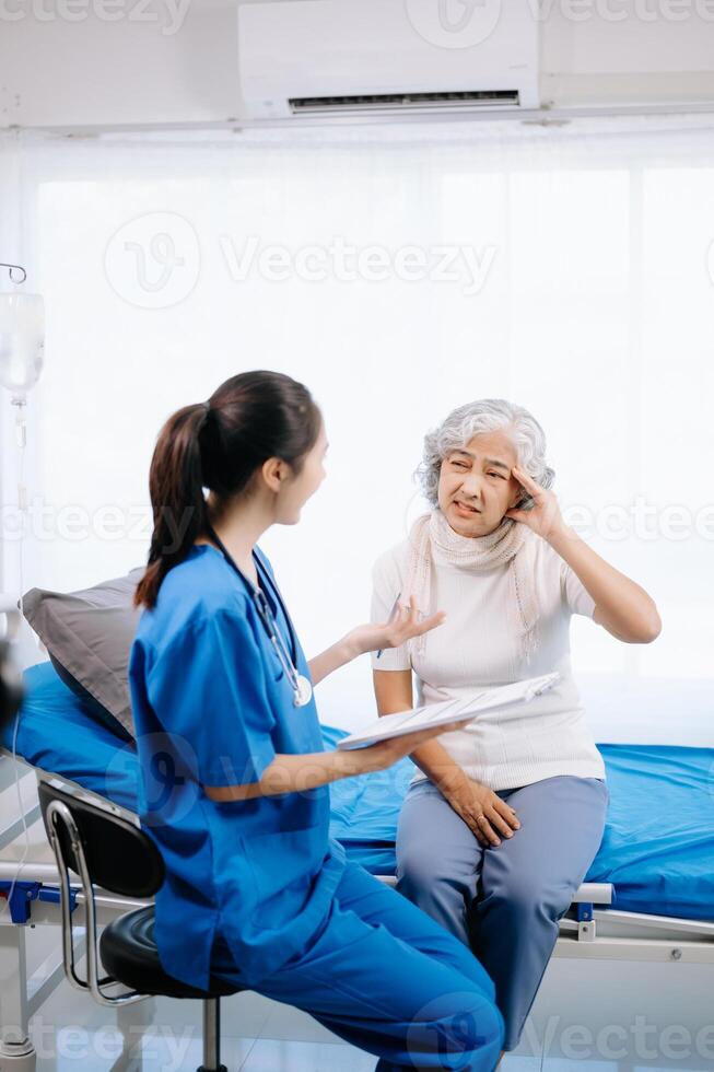 dokter en Aziatisch ouderen geduldig wie liggen Aan de bed terwijl controle pols, raadplegen en leg uit met verpleegster nemen Notitie in ziekenhuis afdelingen. foto