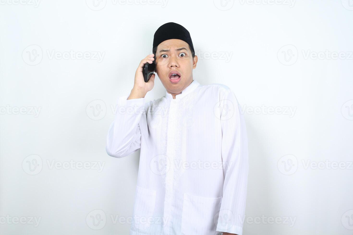 Aziatisch moslim Mens looks geschokt terwijl pratend Aan de telefoon foto