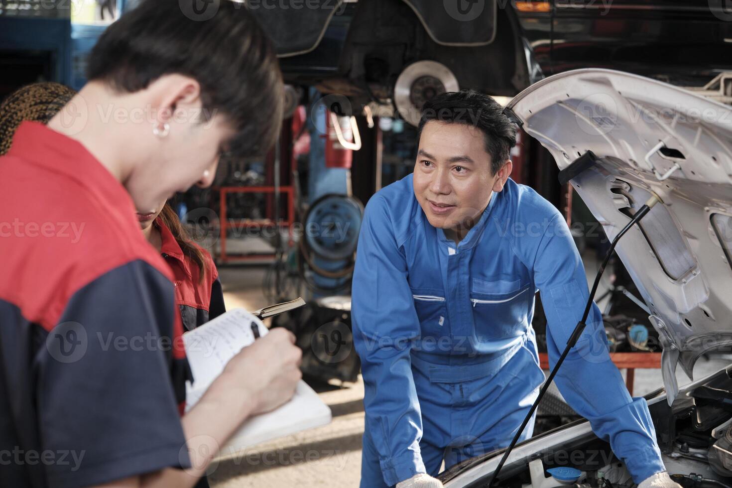 Aziatisch mannetje professioneel automotive ingenieur leidinggevende beschrijft auto motor onderhoud en reparatie werk met monteur arbeider personeel team in fix onderhoud garage, specialist beroepen in auto industrie. foto