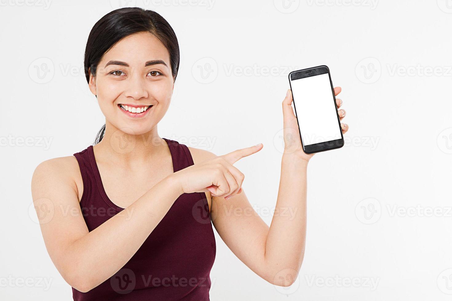 Aziatische, Koreaanse vrouw houdt een lege mobiele telefoon vast, wijst geïsoleerd op een witte achtergrond, hand met zwarte telefoon, kopieer ruimte foto