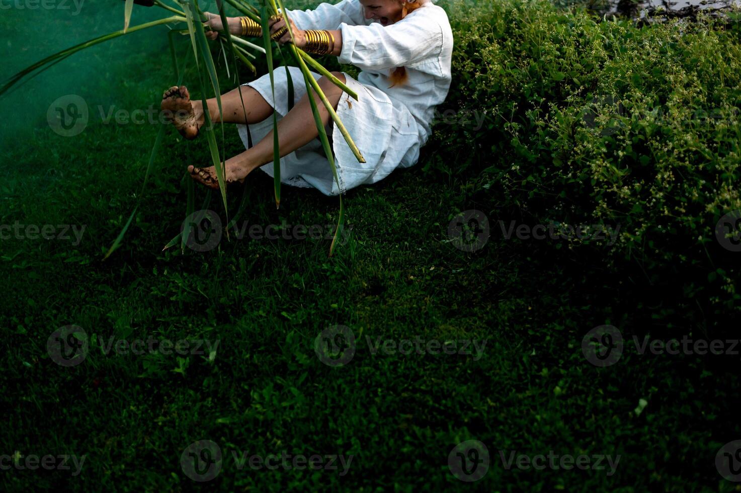 vrolijk jong vrouw met riet dansen in gekleurde rook in een veld- foto