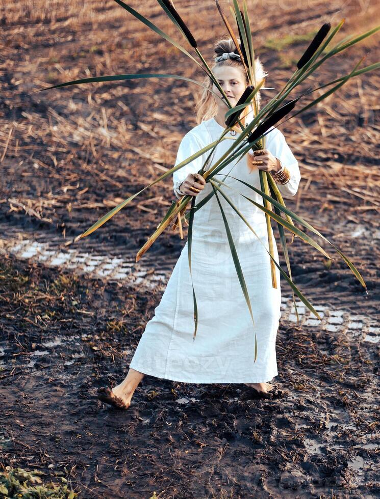 vrolijk jong vrouw met riet dansen in gekleurde rook in een veld. foto