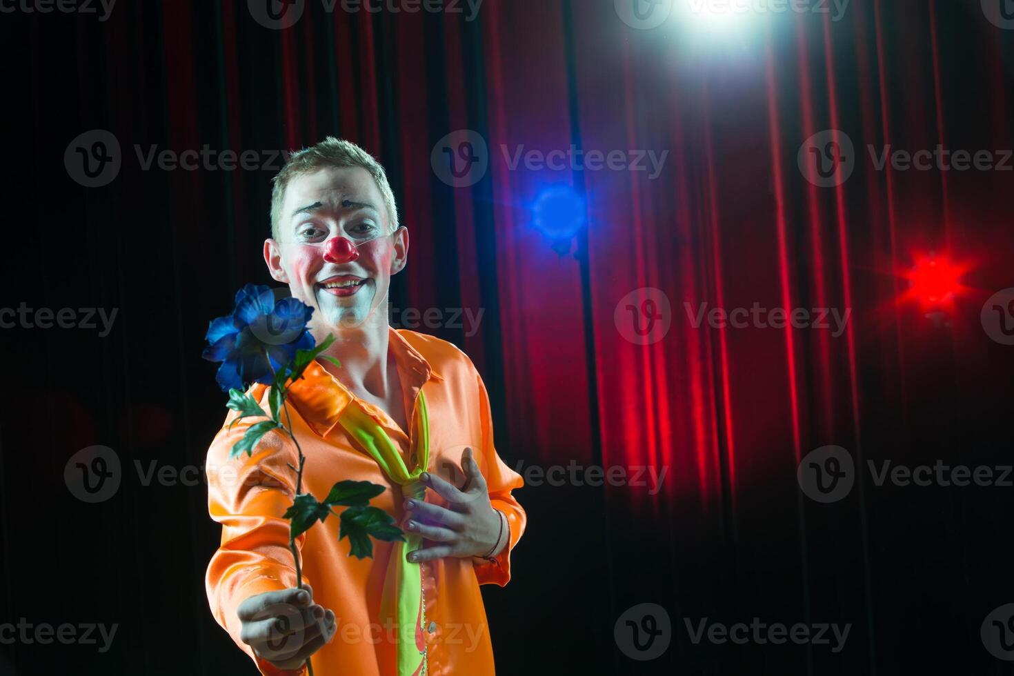 circus clown presteert nummer. een Mens in een clown jurk met een bloem foto