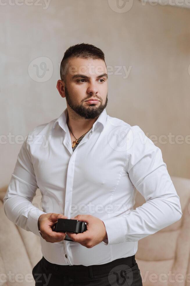 bedrijf shirt. een Mens in een wit overhemd vastmaakt de toetsen. jong politicus, mannetje stijl, zakenman knopen shirt, mannetje handen detailopname, Amerikaans, Europese zakenman foto