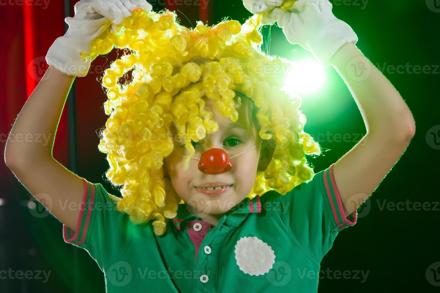 weinig jongen clown. kind in een clown pruik met een rood neus- dichtbij omhoog foto