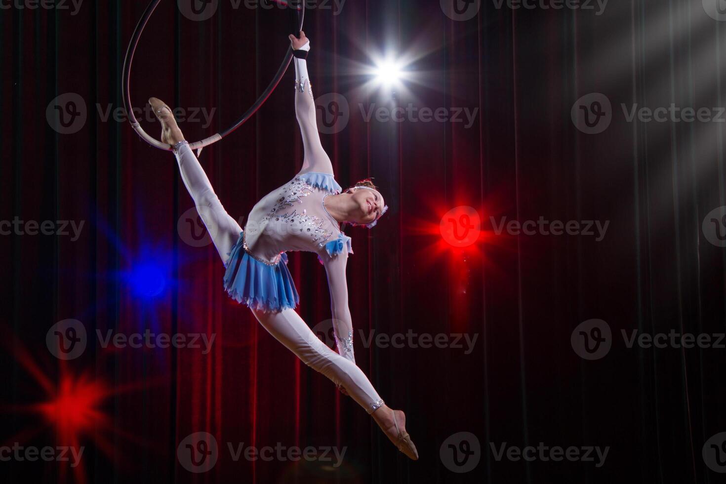 presteert een circus meisje actrice. circus antenne gymnast Aan de hoepel. acrobatiek. tiener presteert een acrobatisch truc in de lucht foto