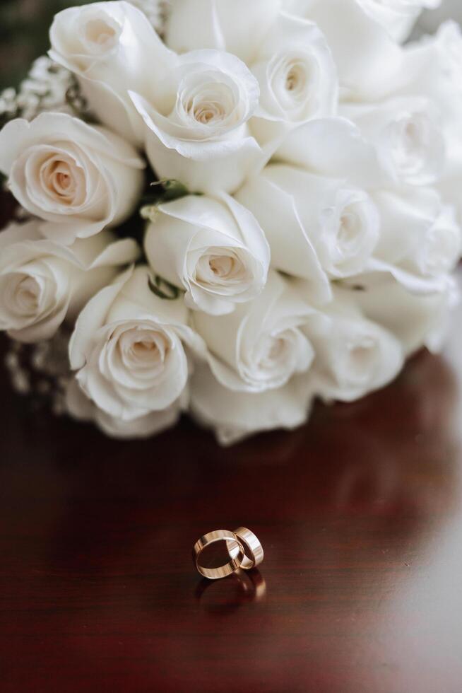bruiloft boeket. wit besnoeiing rozen, groen zaad hoofden en bladeren. groen stengels en wit lint en goud bruiloft ringen. foto