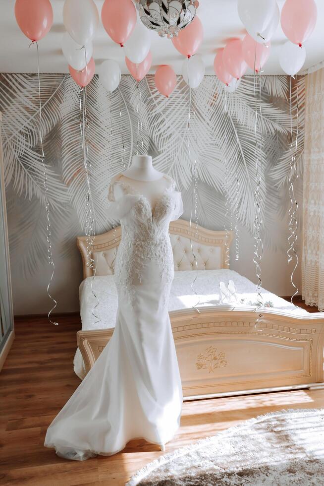 slaapkamer interieur met bruiloft jurk bereid voor de ceremonie. een mooi weelderig bruiloft jurk Aan een mannequin in een hotel kamer. foto