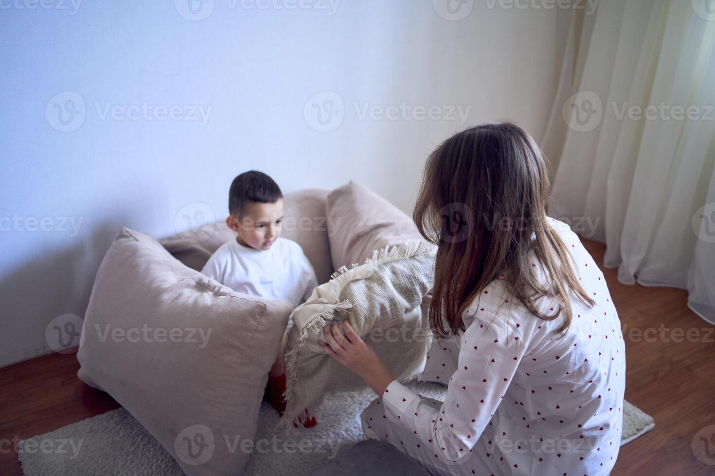 een tiener- meisje bouwt een vesting uit van kussens voor haar weinig broer foto