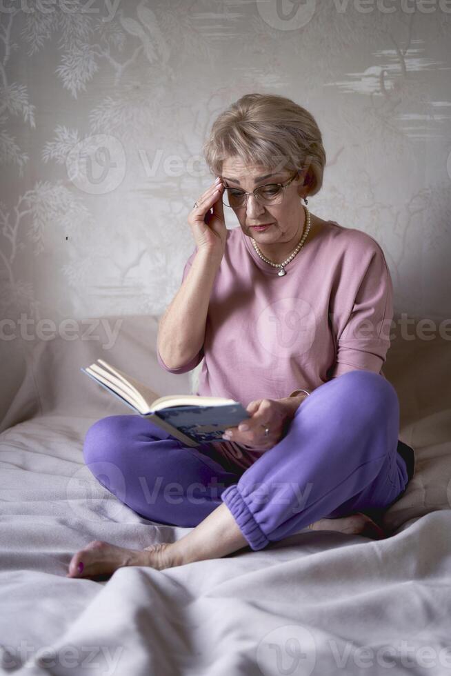 ouderen vrouw leest een boek Bij huis foto