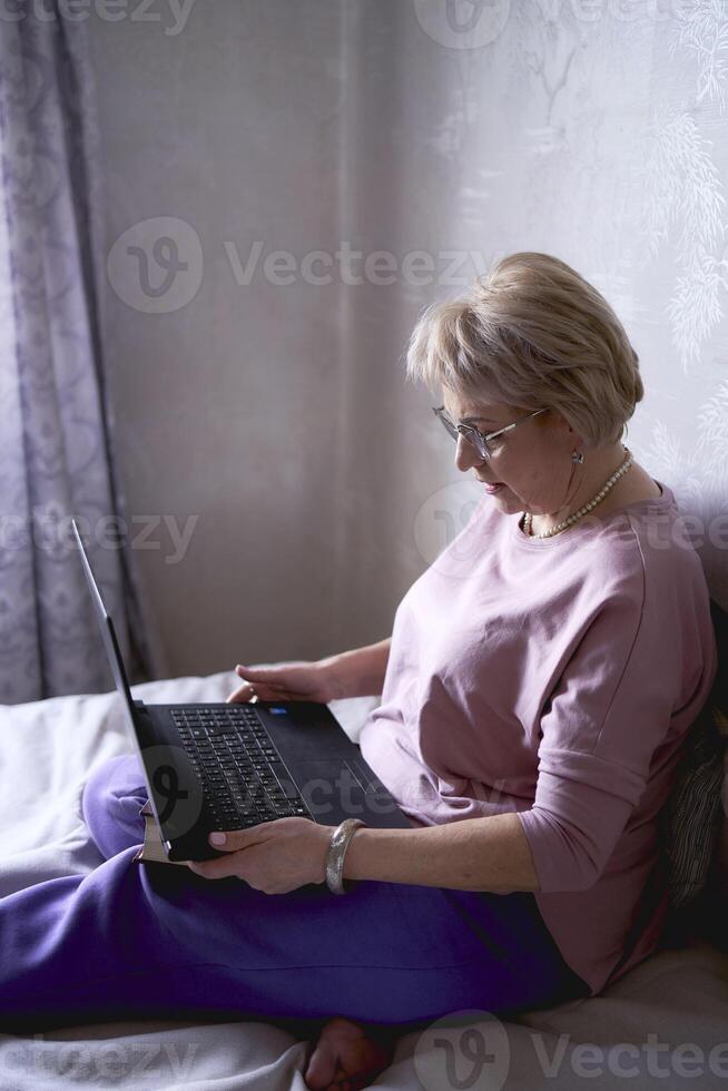 een ouderen vrouw werken met laptop Bij huis foto