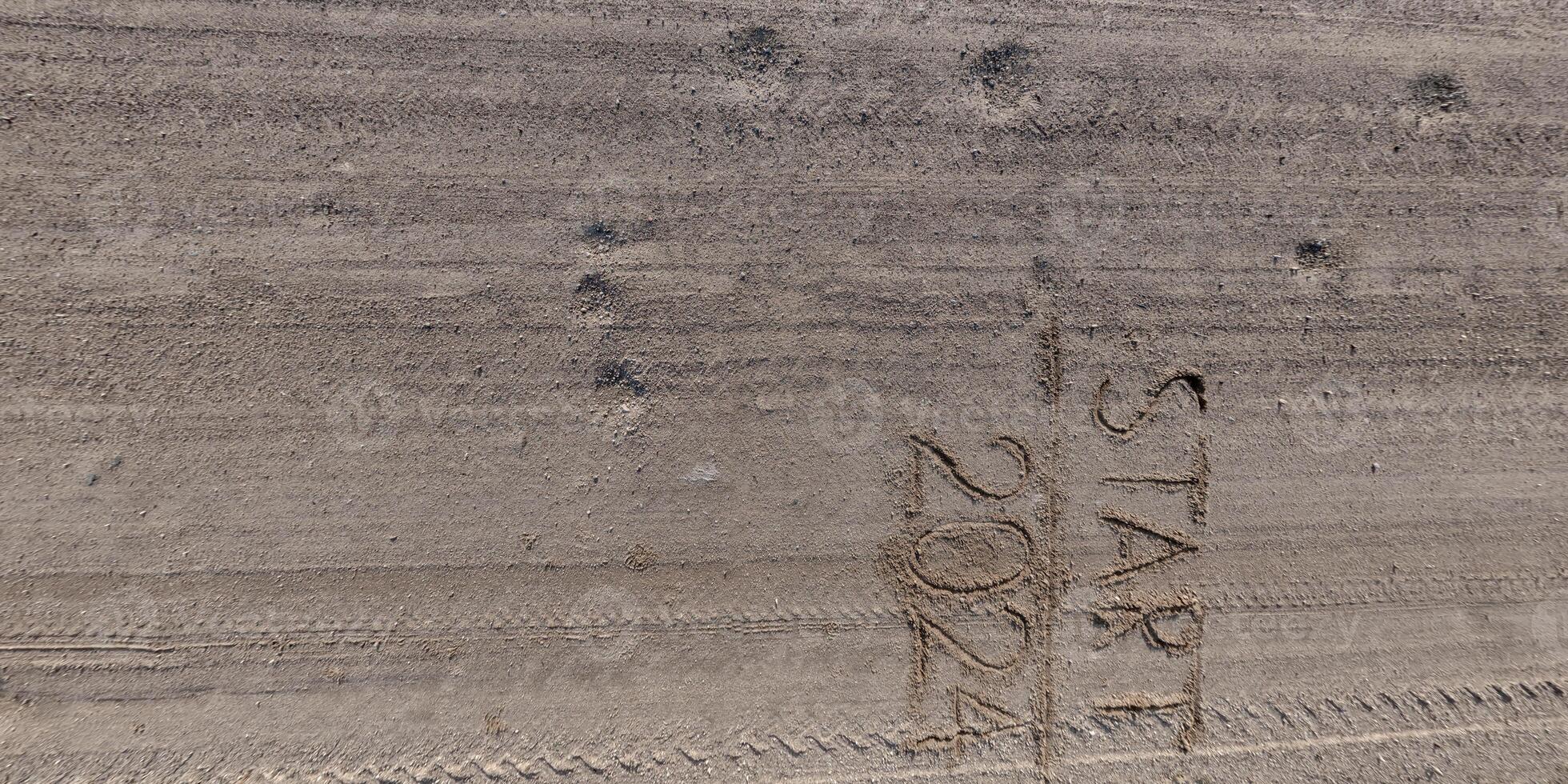 getallen 2024 en begin Aan grind weg van bovenstaand Aan oppervlakte met auto band sporen in platteland foto