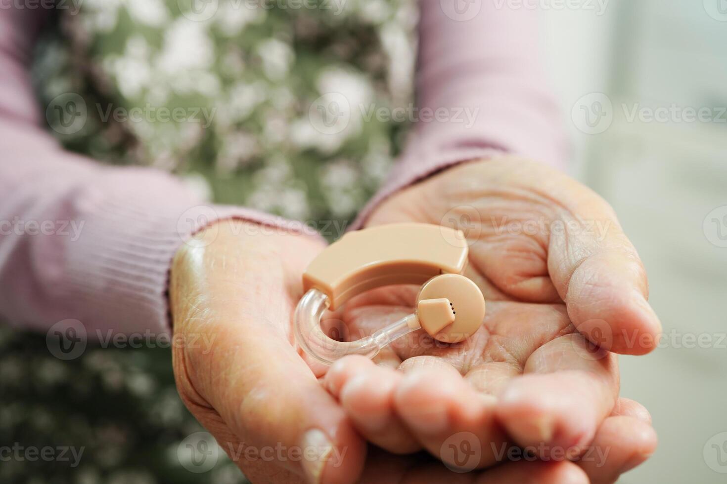 Aziatisch senior vrouw geduldig gebruik makend van horen steun in oor naar verminderen horen verlies probleem. foto