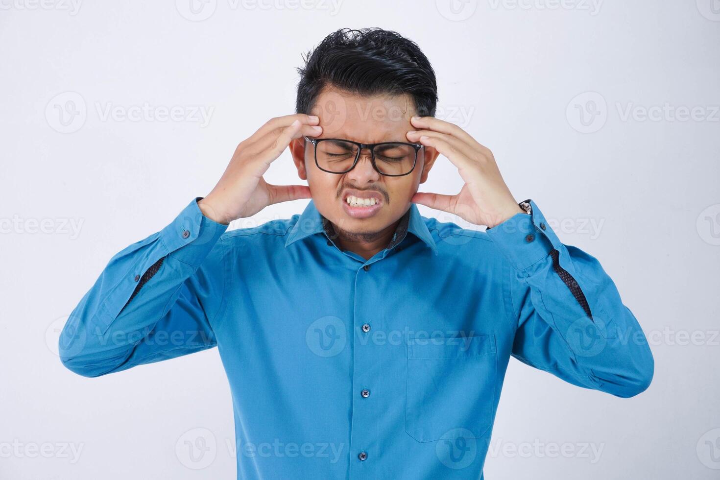 jong Aziatisch Mens in vervelend blauw overhemd Holding hoofd lijden van hoofdpijn omdat migraine en duizelig geïsoleerd Aan wit achtergrond foto