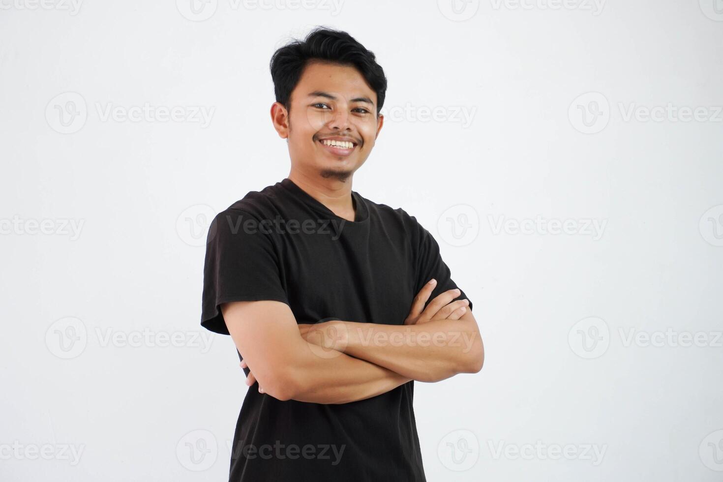 glimlach of gelukkig Aziatisch Mens gekruiste armen en op zoek camera vervelend zwart t overhemd geïsoleerd Aan wit achtergrond foto