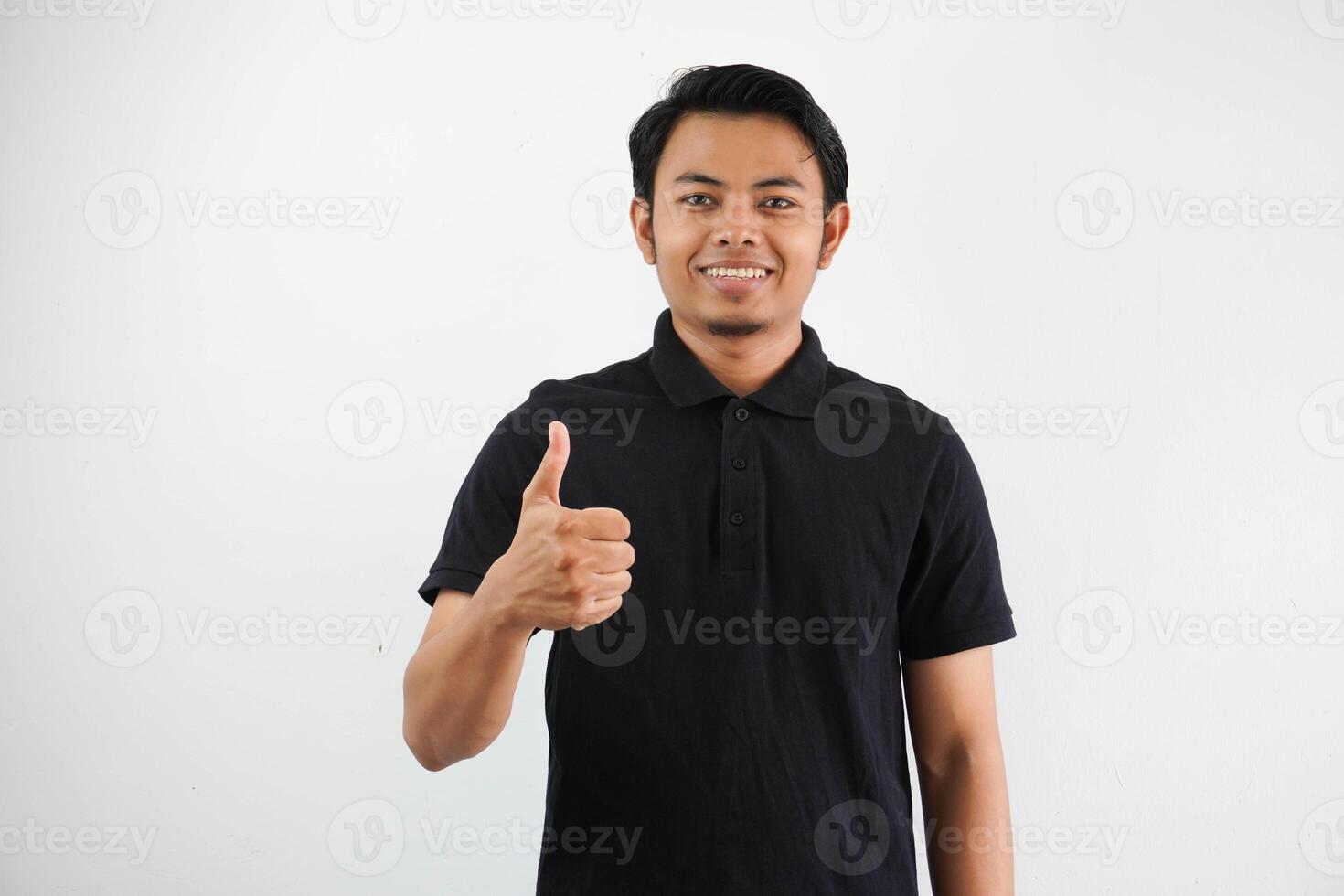 portret van glimlachen jong Aziatisch Mens geven duim omhoog vervelend zwart polo t overhemd geïsoleerd Aan wit achtergrond foto