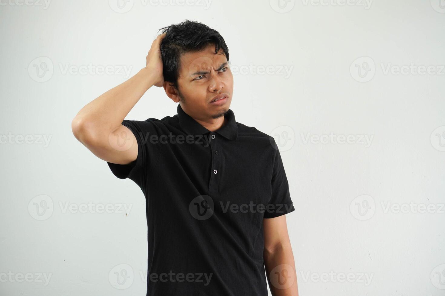 jong Aziatisch Mens in zwart polo t shirt, wit studio backdrop moe en heel slaperig houden hand- Aan hoofd. foto