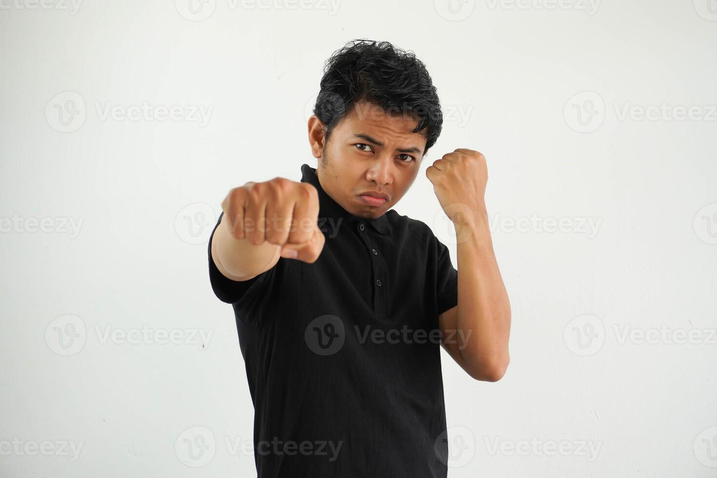 jong Aziatisch Mens tegen een wit studio achtergrond, het werpen een stompen, woede, vechten ten gevolge naar een argument, boksen, vervelend zwart polo t shirt. foto