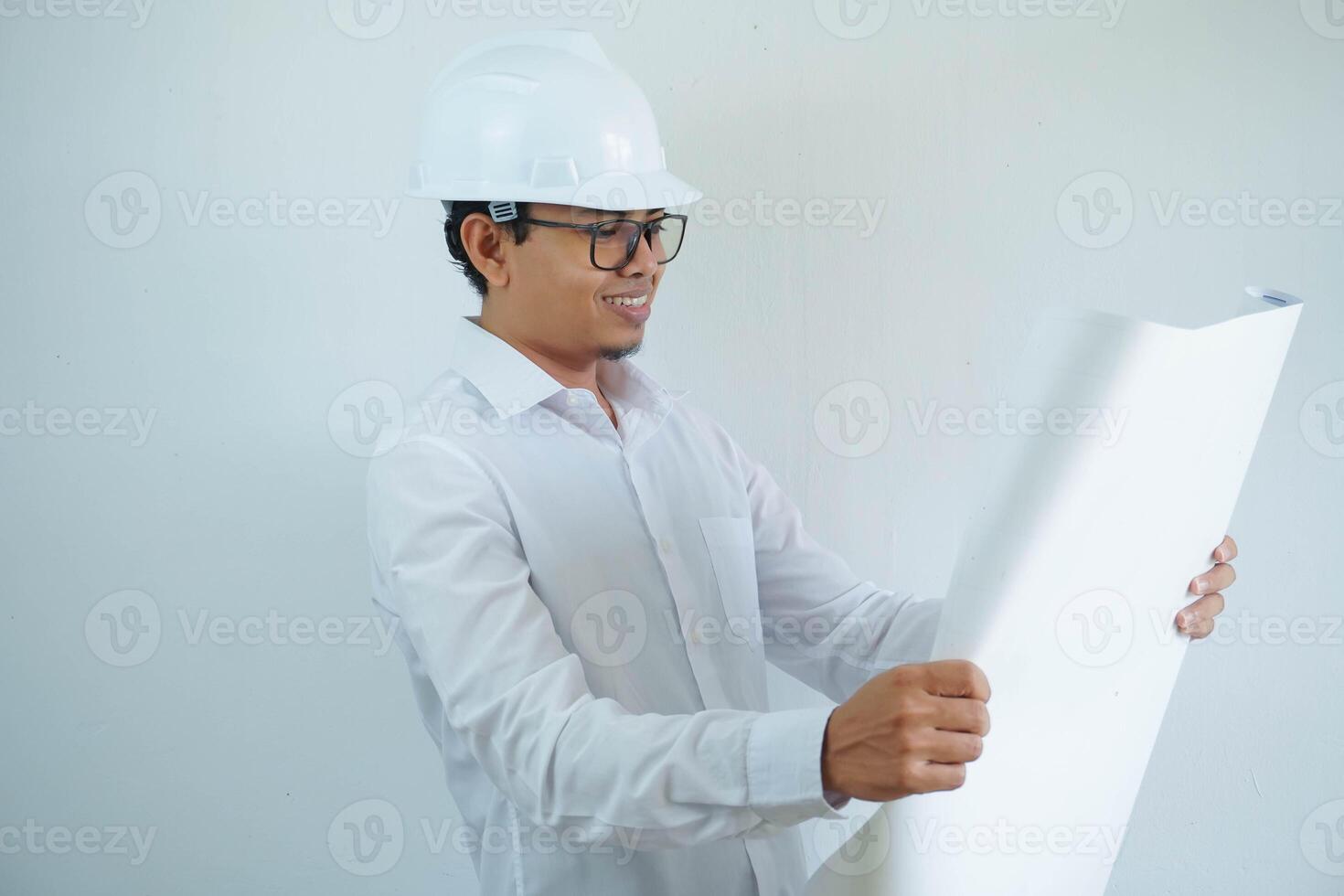 jong Aziatisch mannetje architect ingenieur glimlachen en Holding bouwkunde blauwdrukken geïsoleerd Aan wit achtergrond. foto