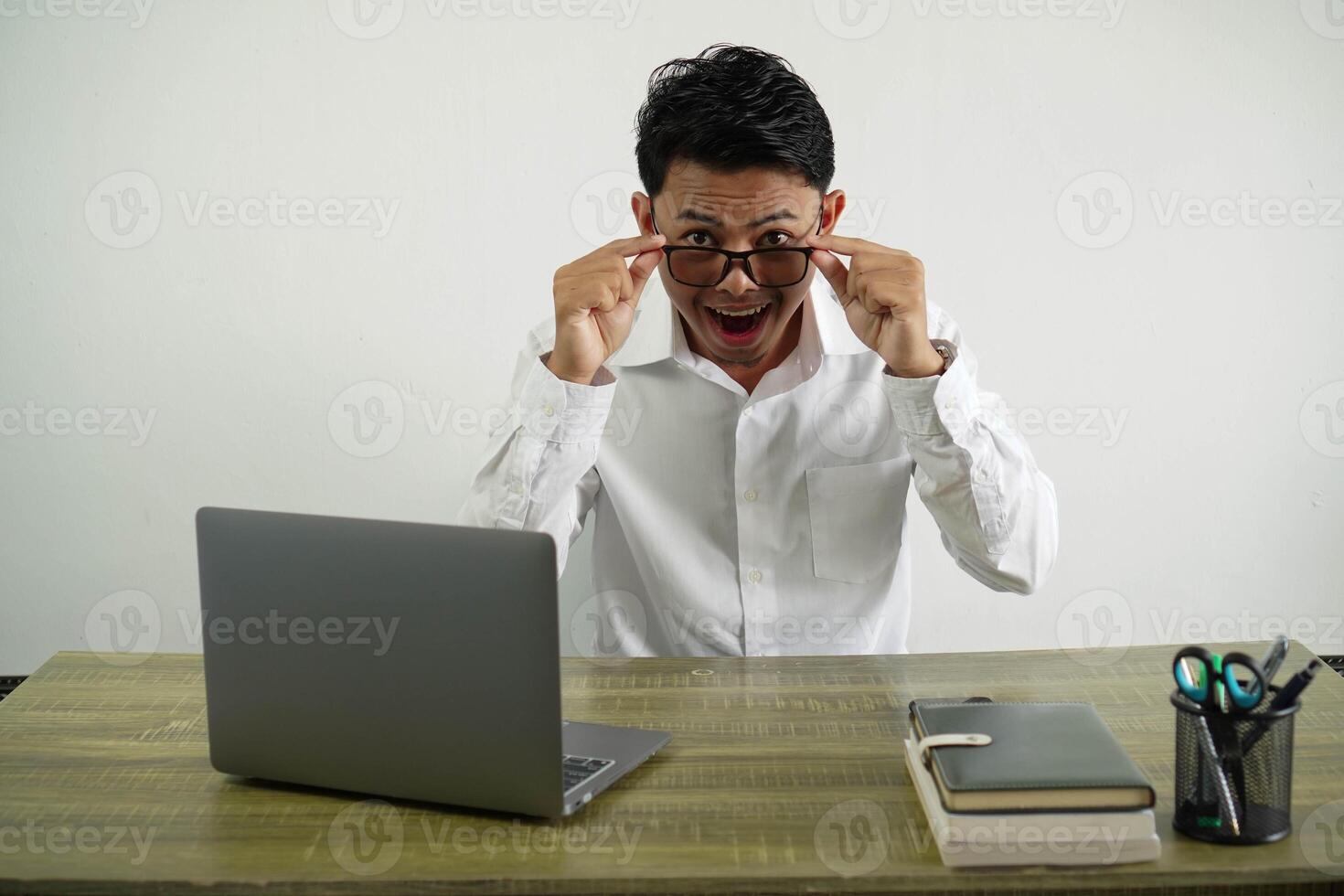 verrast jong Aziatisch zakenman in een werkplaats Open mond met Holding bril slijtage wit overhemd geïsoleerd foto