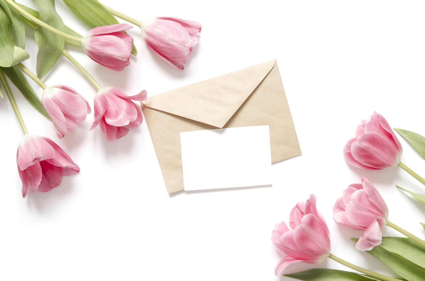 bloemen achtergrond met tulpen bloemen en kraft envelop. vlak leggen, top visie. lief groet kaart met tulpen voor moeders dag, bruiloft of gelukkig evenement foto