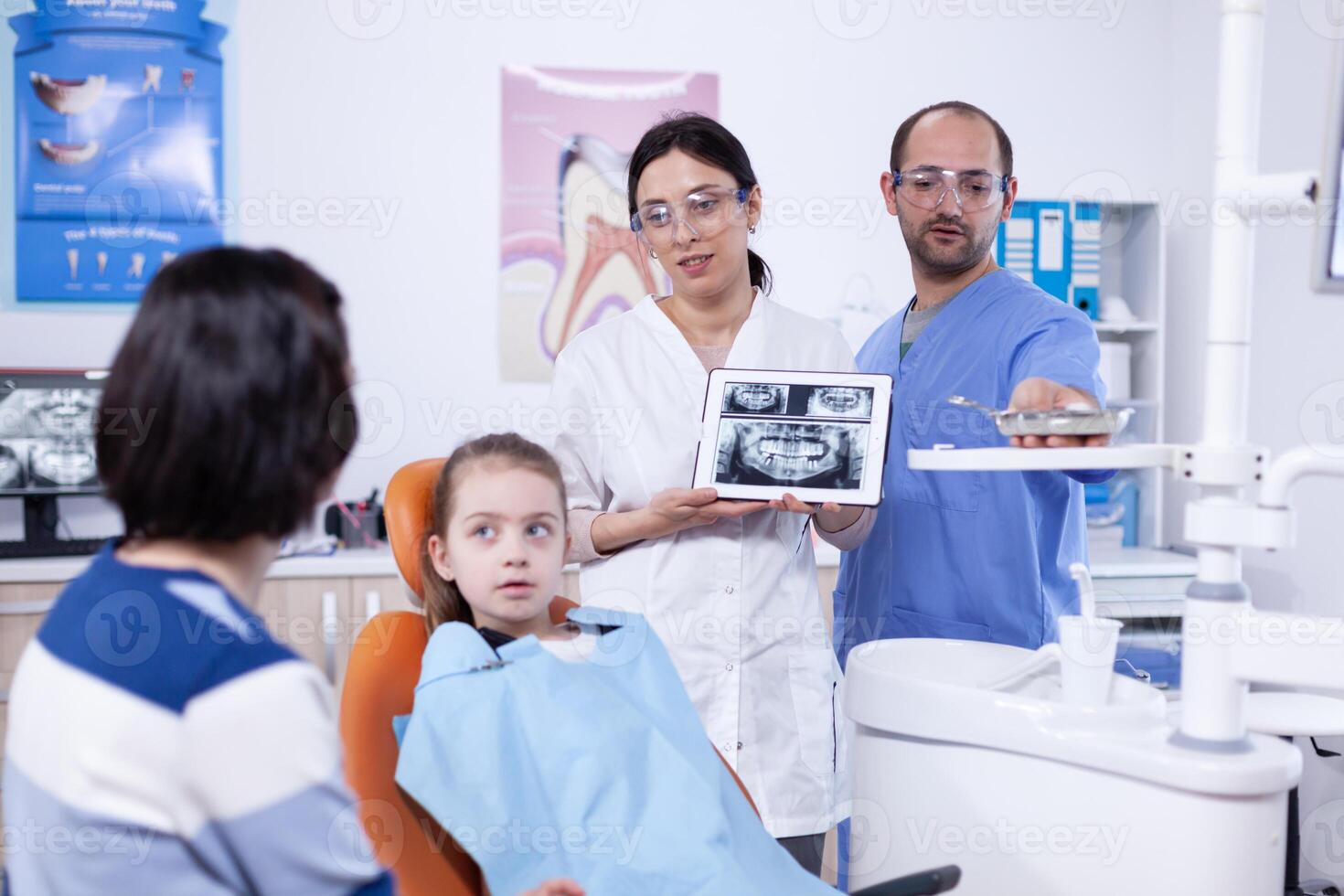 tandarts bespreken over holte het voorkomen met weinig meisje ouder stomatoloog uitleggen tanden diagnose naar moeder van kind in Gezondheid kliniek Holding röntgenfoto. foto