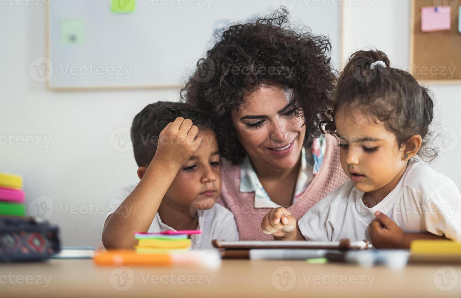 leraar met kinderen gebruik makend van digitaal tablet in peuter- klas - onderwijs en technologie concept foto