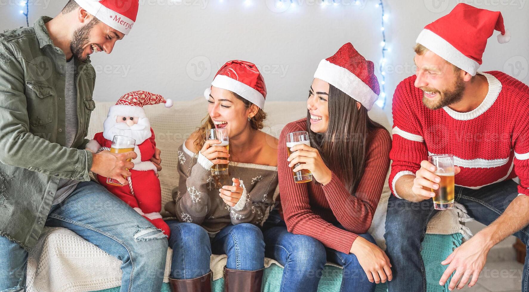gelukkig vrienden hebben pret gedurende Kerstmis tijd zittend Aan sofa Bij huis - jong mensen drinken bier samen en genieten van Kerstmis vakantie - jeugd viering Kerstmis concept foto